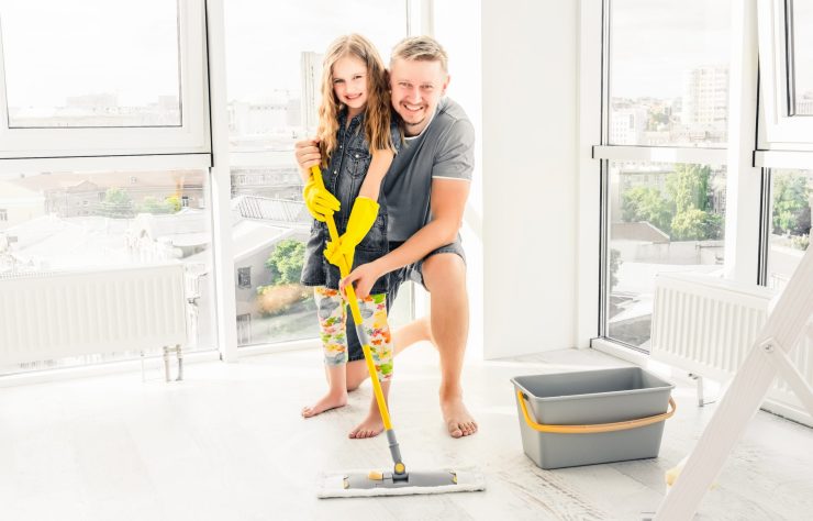 Daughter and father have fun cleaning the floor
